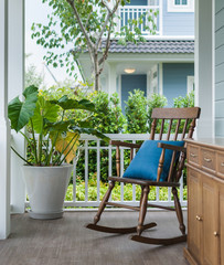 wooden rocking chair on front porch with pillow