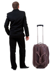 back view of business man in black suit traveling with suitcas .