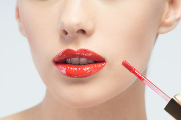 Beautiful woman applying lip gloss