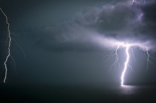 Bolt of lightning stricking through a cloud into the ocean