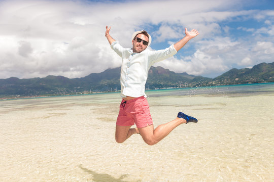 happy young man jumping of joy on the beach