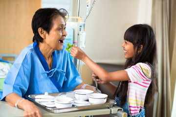 Granddaughter is feeding her grandmother with vegetable