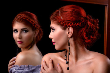 Young elegant woman looking in the mirror
