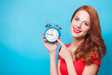Redhead girl with alarm clock on blue background.