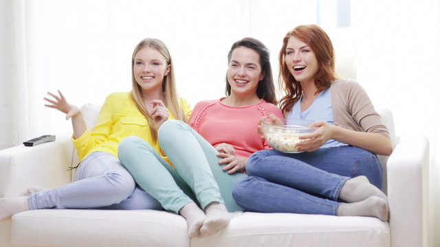 three smiling teenage girls watching tv at home