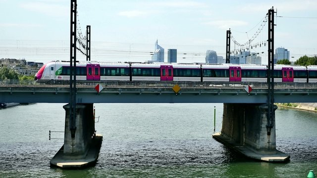 RER (urban and intercity train) crossing bridge over the Seine river; La Defense business area in the background