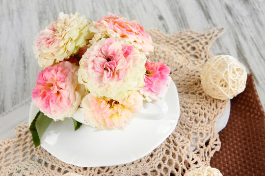 Roses in cup on napkins on  wooden background