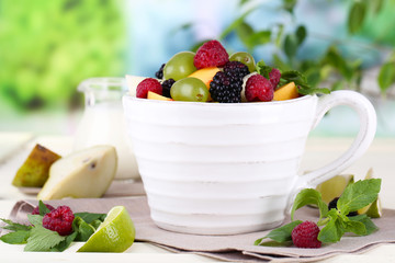 Fruit salad in cup on wooden table on nature background