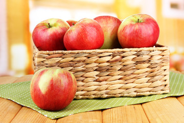 Ripe apples in wicker basket, on bright background