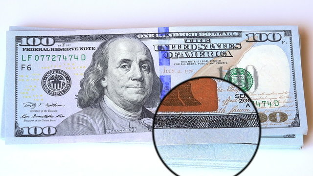 magnifying glass on corners of 100 dollars bill new