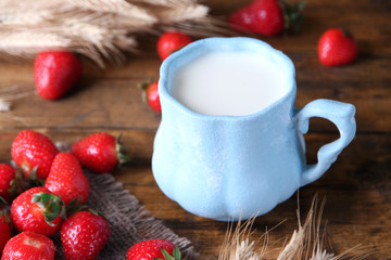 Ripe sweet strawberries and mug with milk