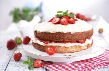 Delicious biscuit cake with strawberries on table close-up