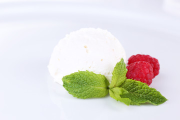 Creamy ice cream with raspberries and mint leaves isolated