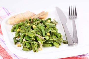 Salad with green beans and corn on plate, isolated on white