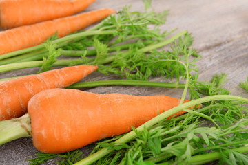 Fresh carrot with leaves on wooden background