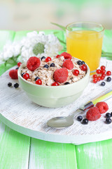 Tasty oatmeal with berries on table on bright background