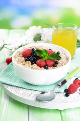 Tasty oatmeal with berries on table on bright background