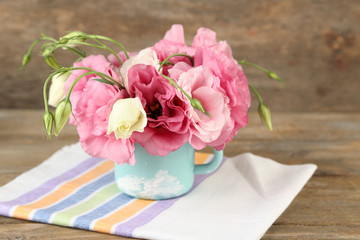 Bouquet of eustoma flowers in vase on wooden background
