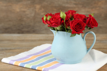 Bouquet of red roses in vase on wooden background