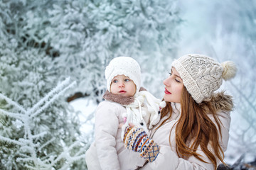 Fototapeta na wymiar Mother holds daughter on hands in winter forest