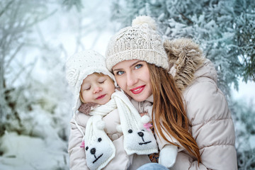 Mother holds daughter on hands in winter forest