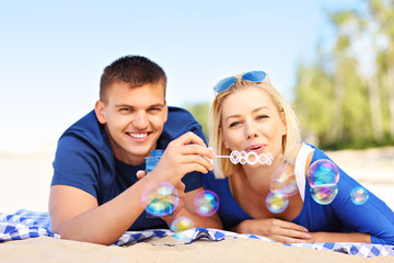 Young couple blowing bubbles at the beach