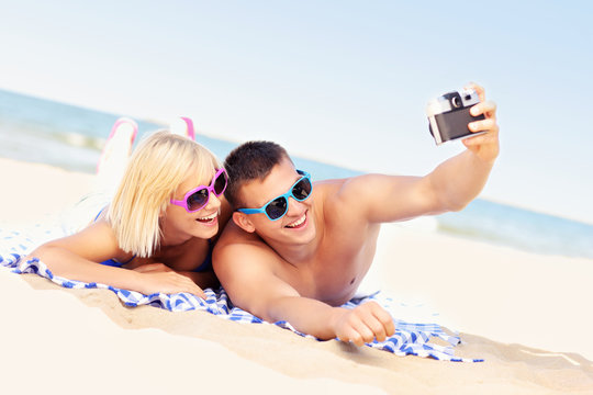 Happy couple taking pictures at the beach