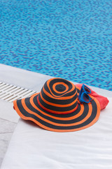 Fototapeta na wymiar Sunbathing accessories on beach towel by a swimming pool