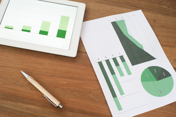 Tablet with graphs and charts on wooden table