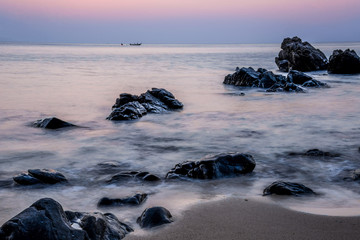 Pink sky over a rocky seashore. Sunset landscape. Thai Boat. Tro