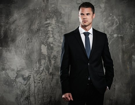 Well-dressed man in black suit against grunge wall