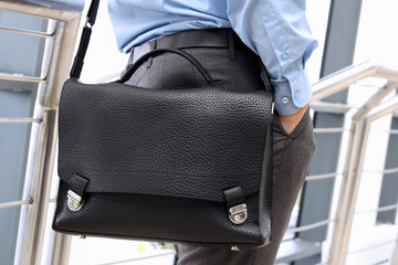 Businessman standing  and holding  a  leather briefcase on his s