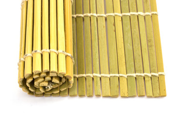 Rolled straw mat over white background, top view