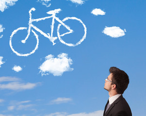 Young man looking at bicycle clouds on blue sky