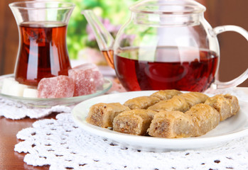 Sweet baklava on plate with tea on table in room