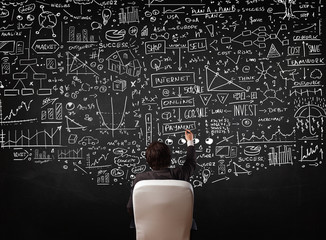 Businessman sitting in front of a blackboard with charts