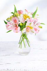 Alstroemeria flowers in vase on table on light background