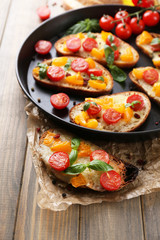 Tasty bruschetta with tomatoes on pan, on old wooden table