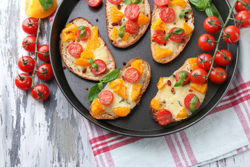 Tasty bruschetta with tomatoes on pan, on old wooden table