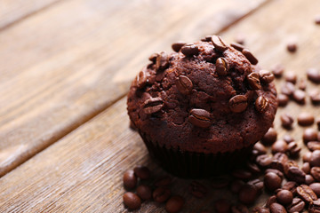 Chocolate muffin and coffee grains on wooden background