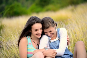 Two beautiful young women laughing on dry grass