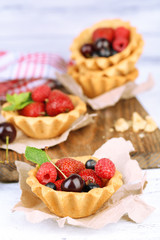 Tasty tartlets with berries on wooden table