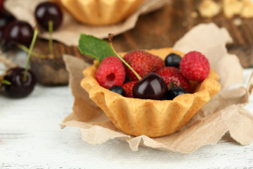 Tasty tartlets with berries on wooden table