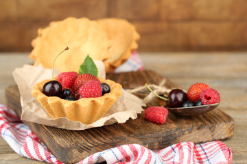 Tasty tartlets with berries on wooden table