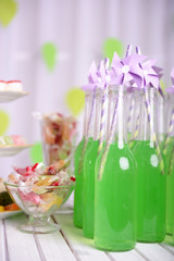Bottles of drink with straw and sweets on decorative background