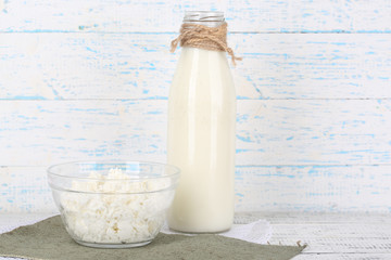 Glass bottle of milk and cottage cheese on wooden background