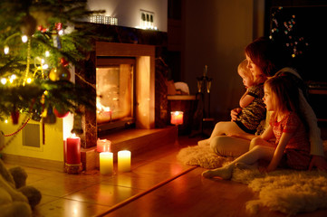 Fototapeta na wymiar Happy family by a fireplace on Christmas