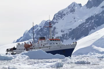 Fotobehang tourist ship among the icebergs on the background of the mountai © Tarpan