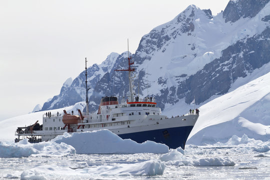 tourist ship among the icebergs on the background of the mountai