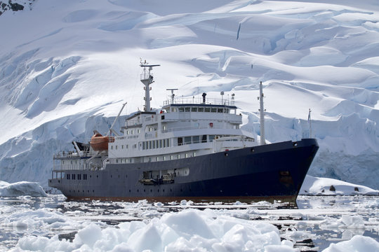 big blue tourist ship in Antarctic waters against the backdrop o